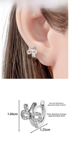 Macro detail of silver bow earrings with zircon stones and precise size dimensions
