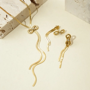 Golden infinity bow necklace and tassel earrings set with clear crystals and snake chains