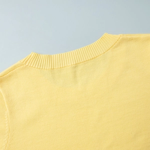 Detailed close-up of a light yellow knitted crew neck top with ribbed collar detail