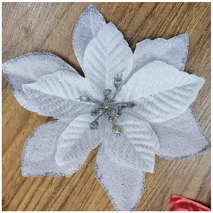 Close-up of silver glitter artificial poinsettia flower on a warm wooden background