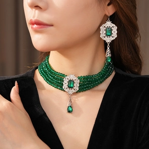 Close-up of vintage emerald choker and matching drop earrings on a velvet garment