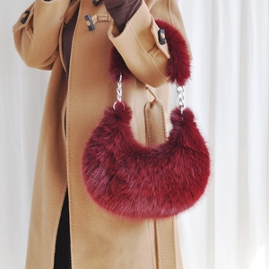 Detail of burgundy plush hobo bag featuring fluffy faux fur and silver metal chain strap