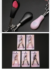 Detail view of pink and black eyelash curlers with beauty tools packaging and comb attachment