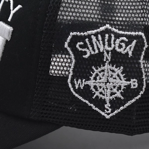 Detailed close-up of side mesh and white embroidered SINUGA compass badge on baseball cap