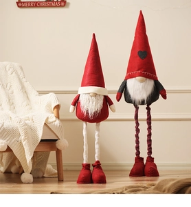 Close-up of red and grey plush Christmas gnomes on wooden floor with festive decor