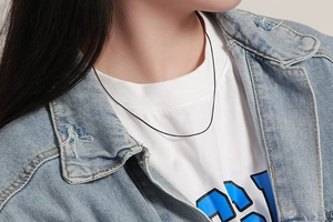 Detail of a minimalist thin black snake chain necklace worn on a woman's neck