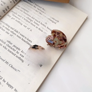 Detail von zwei herzförmigen Acetat-Haarklammern in Schildpatt- und Marmoroptik auf Buch