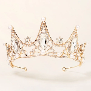Macro shot of gold bridal tiara with rhinestones and white pearls on cream background