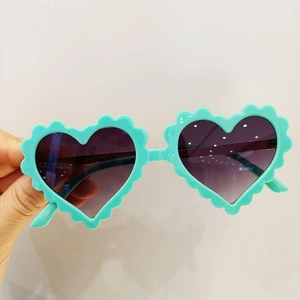 Détail de lunettes de soleil coeur vert menthe avec bords festonnés et verres dégradés