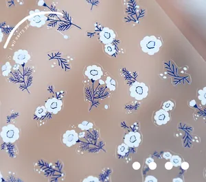 Detailed macro view of thin floral nail stickers with white daisies and blue petals