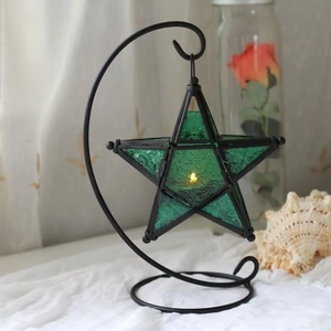 Detail of star shaped green embossed glass lantern on a black crescent moon metal stand