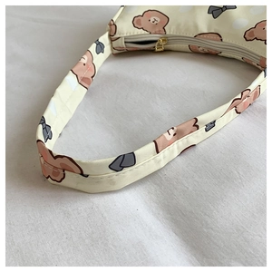 Close-up of beige fabric shoulder strap featuring cartoon bear and bow tie patterns