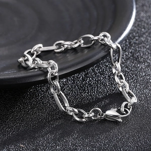 Detailed view of silver stainless steel chain bracelet with lobster clasp on dark tray