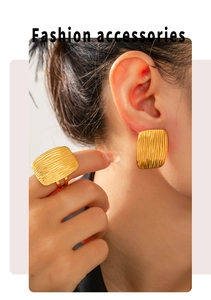 Detail of gold titanium steel set showing layered line texture on square ring and earring