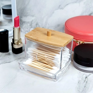 Portable acrylic cotton swab holder with bamboo lid on marble vanity surface