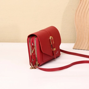 Side view of red multi-pocket crossbody bag with pebble texture and metallic buckle