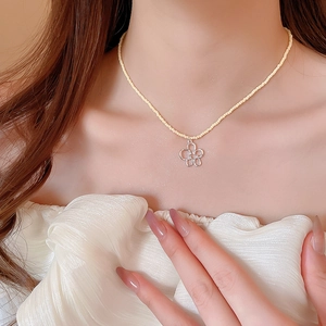 Dettaglio girocollo di perline gialle con ciondolo a fiore in zircone argento sul collo