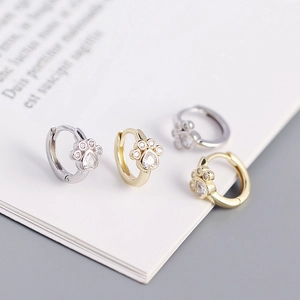Macro shot of silver and gold cat paw earrings featuring heart-shaped cubic zirconia