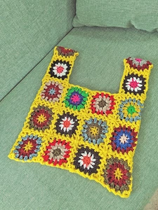 Close-up of handmade crochet tote bag featuring colorful granny square floral patterns