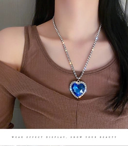 Detailansicht der silbernen Herzkette mit großem blauem Edelstein und kleinen Diamanten