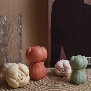 Artistic tulip-shaped scented candles in pastel colors placed on a woven mat