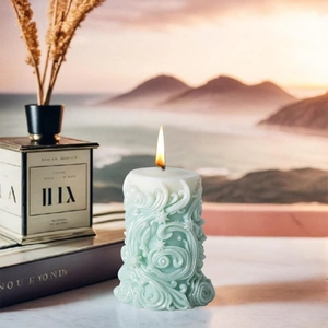 Vela aromática cilíndrica verde menta con elegantes texturas onduladas y tallas de estrellas