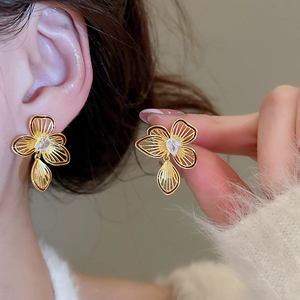 Detailed close-up of a gold flower earring featuring a teardrop zircon and leaf pendant