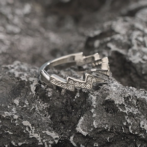 Silver lighting bolt ring with clear zircon crystals on dark textured stone background