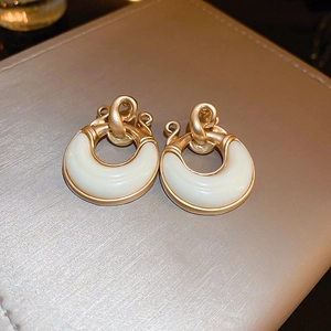 Detailed view of vintage gold horseshoe earrings with cream resin on a beige leather surface