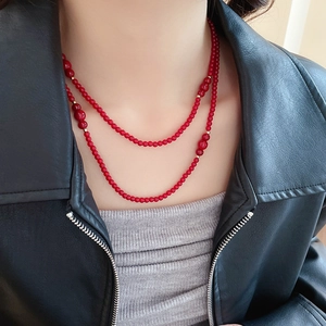Close-up of double-layered red beaded necklace with golden spacer beads on a model