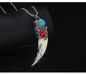 Detailed shot of ethnic faux wolf tooth pendant with red and blue inlaid stones
