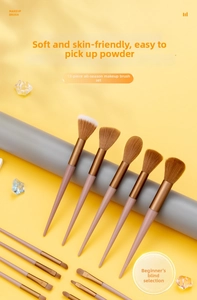 Close-up of 13 professional makeup brushes with pink handles on a yellow background
