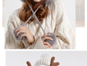 Close-up of thick knitted winter hat with white antlers and soft plush pom-pom details