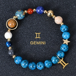 Macro shot of 8mm Gemini zodiac blue natural stone beads with gold charms on black
