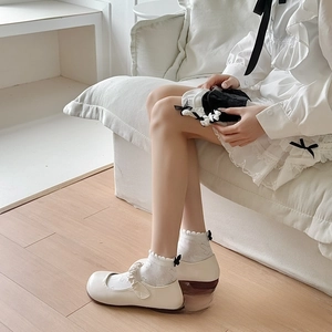 Close-up of white JK socks with elegant lace ruffles and small black bows