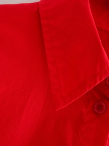 Detail eines roten Baumwollhemdes mit spitzem Kragen und passendem Harzknopf-Detail
