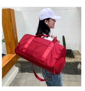 Detailed side view of the large red travel bag being worn by a model in outdoor setting