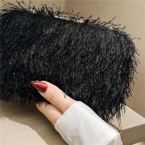 Detail shot of black fringe evening clutch bag with gold chain and metal clasp