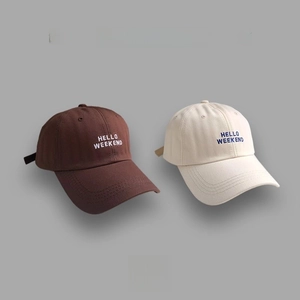 Detail of HELLO WEEKEND embroidery on beige and brown cotton baseball caps