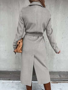 Detail of grey wool coat showing waist belt and back split on a minimalist background