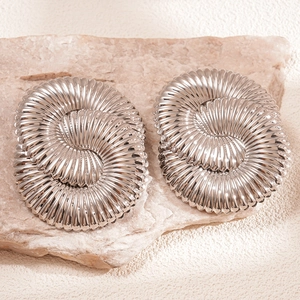 Gros plan détaillé de boucles d'oreilles spirales argentées avec texture radiale sur pierre