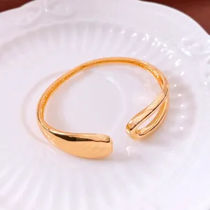 18K gold plated asymmetric open cuff bracelet with polished teardrop design on white plate