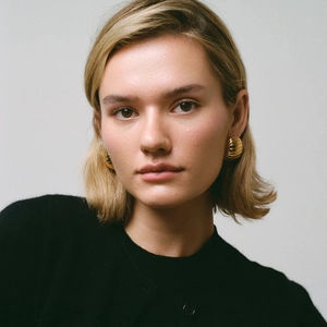 Close-up of gold stainless steel oval ribbed chunky earring on model's ear