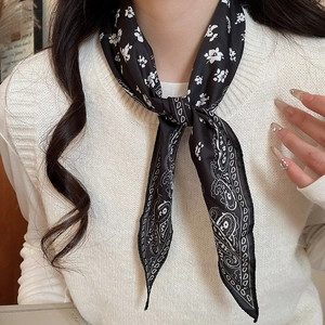 Close-up of black silk scarf necklace with white floral prints and paisley patterns