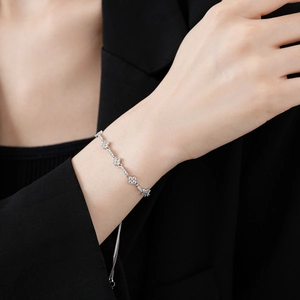 Macro shot of silver zircon flower bracelet worn by a model against a dark blazer