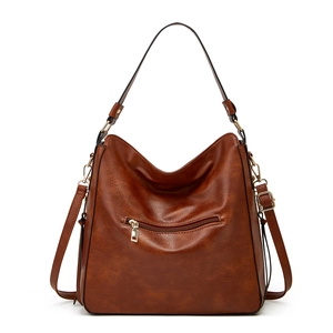 Detail view of brown leather tote bag with metallic zipper pocket and adjustable strap