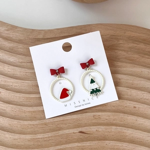 Detailed shot of Christmas earrings with red bow, Santa hat and green tree pendant