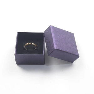 Golden oval link ring displayed in a purple textured gift box with black lining