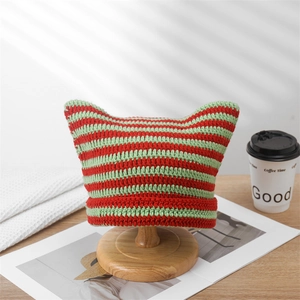 Detail of red and green striped knit beanie with cute cat ears on a wooden hat stand
