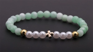 Détail du bracelet en perles avec cristaux verts, perles et pendentif croix dorée